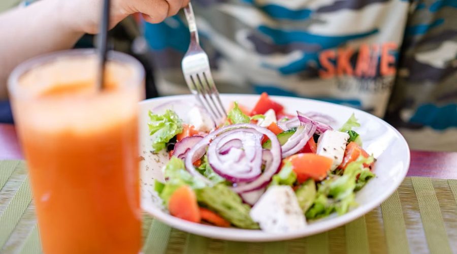 Colorful salad with fresh vegetables and a refreshing drink on a table.
